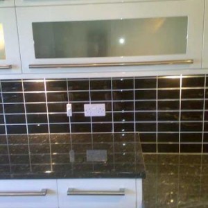 Black kitchen tiles with large neutral units.