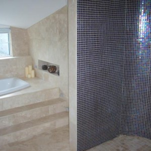 trav bathroom with sunken bath and purple mosaic shower cubicles