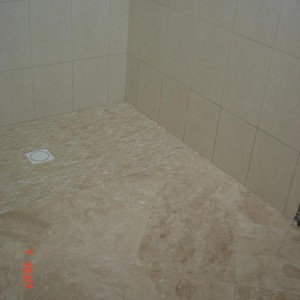 F&H Travertine bathroom floor meeting tumbled mosaic tray & glazed ceramic tile on the walls, with mosaic border as the tray