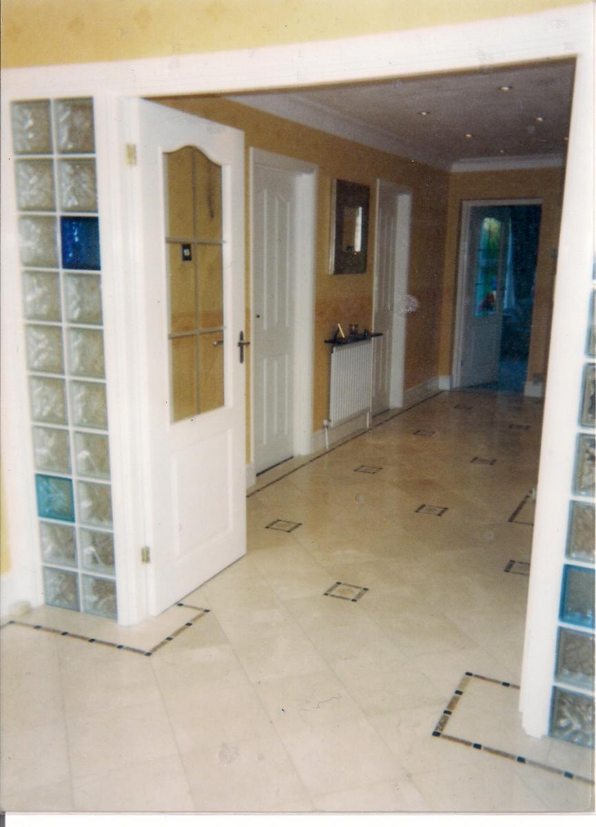 ENTRANCE HALLWAY 'IN' - 300X300MM CREMA MARFIL MARBLE WITH INSETS AND INLAY BORDER IN NOCHE /BLACK TUMBLED MARBLE.