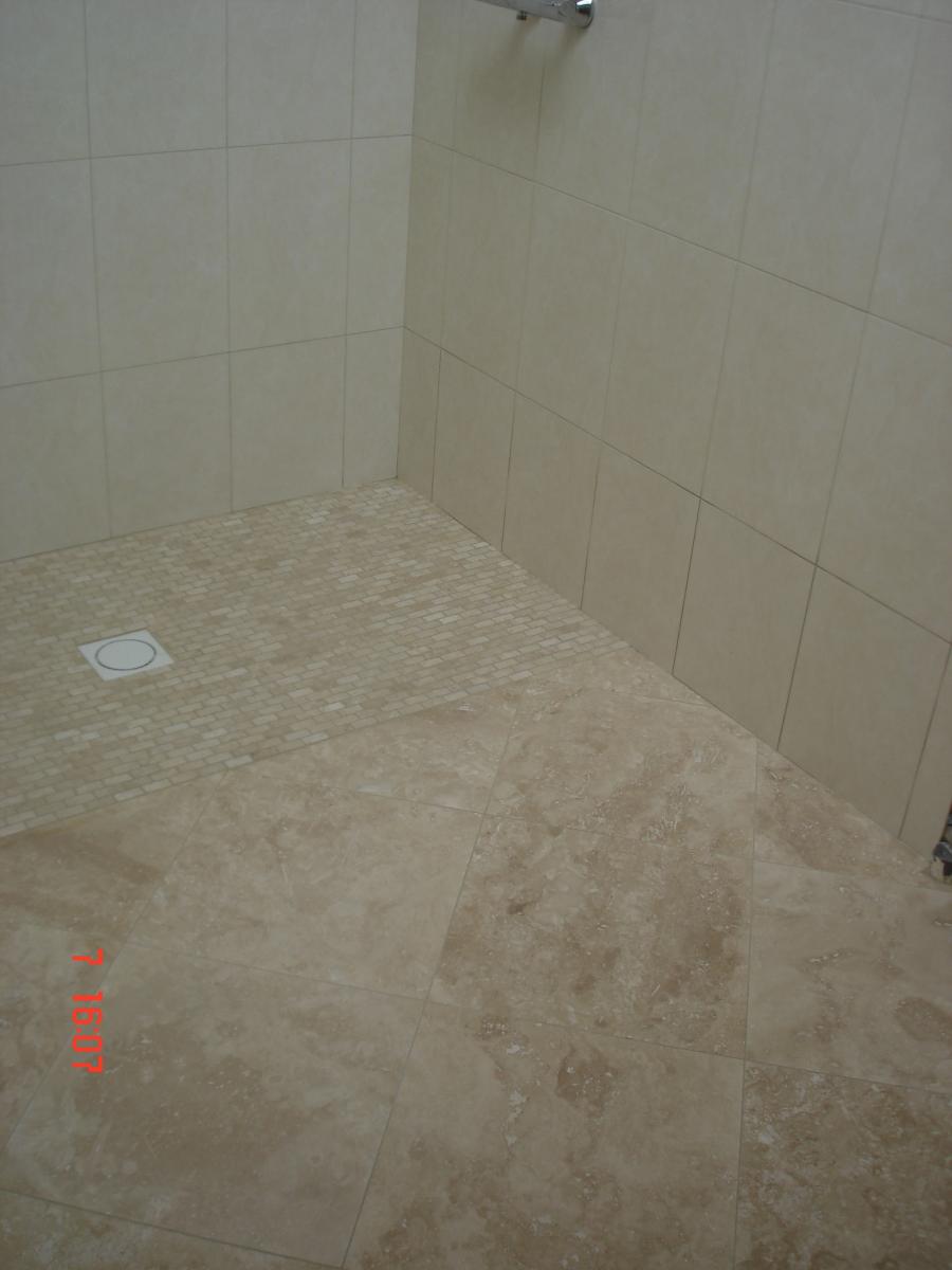 F&H Travertine bathroom floor meeting tumbled mosaic tray & glazed ceramic tile on the walls, with mosaic border as the tray